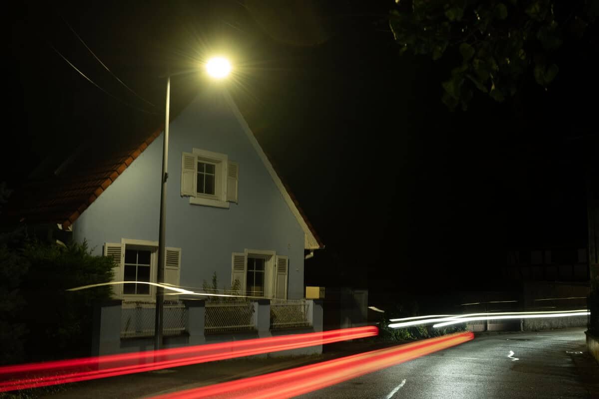 Rue résidentielle de nuit à Strasbourg, traînées de phares sous un candélabre