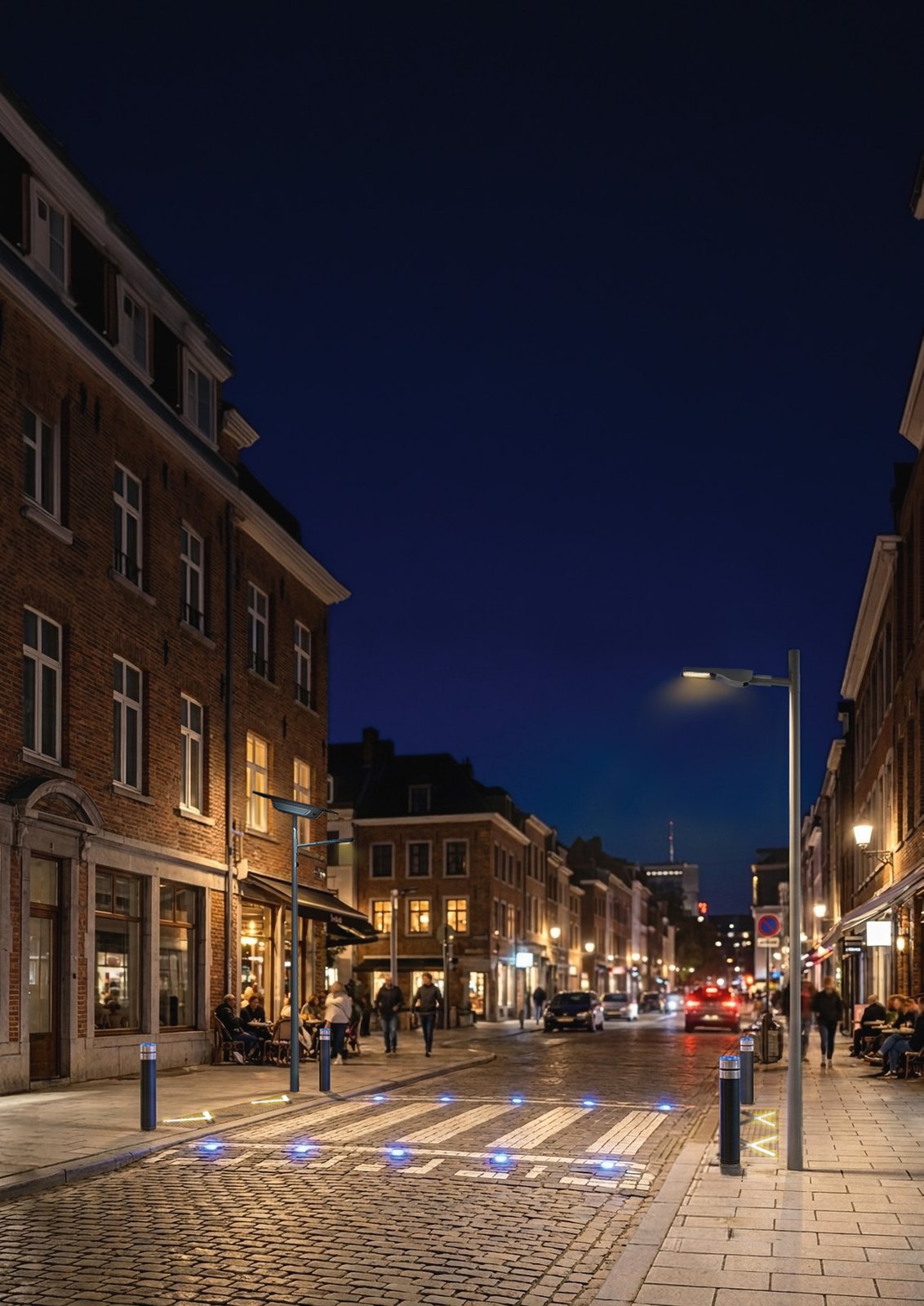 Vue d'ensemble d'une rue de nuit équipée par le Groupe Ragni : luminaires à optique dédiée, potelets lumineux et plots balisant le passage piéton