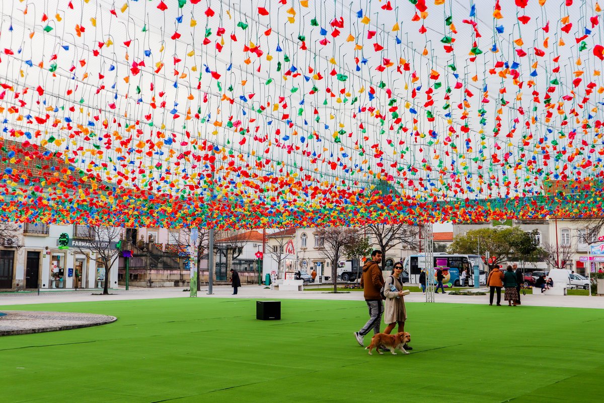Plafond climatique de fanions colorés au-dessus d'une place piétonne, promeneurs sur la pelouse