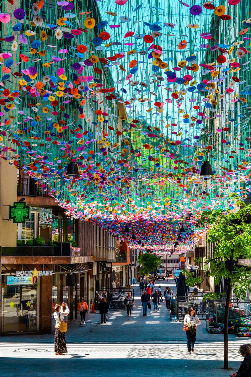 Plafond climatique Ximénez au-dessus d'une rue commerçante : fleurs colorées suspendues, passants à l'ombre